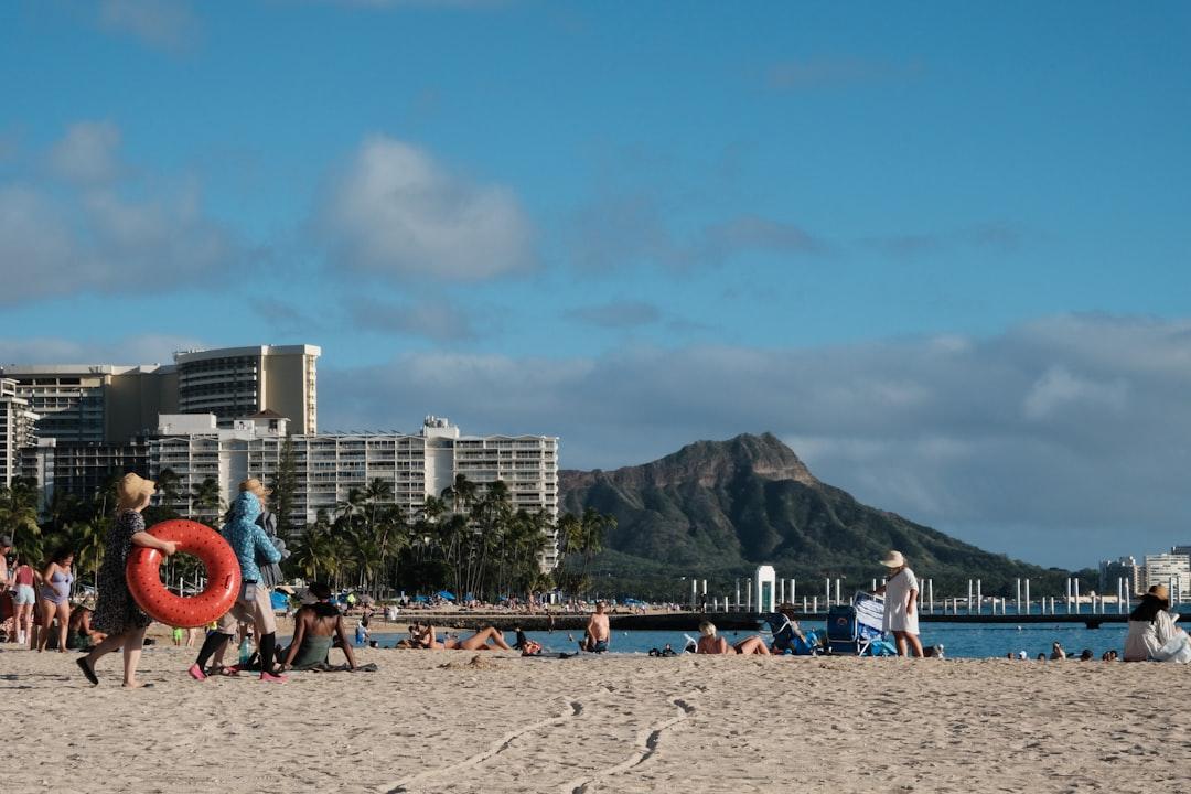 A group of people walking on a beach next to a body of water
